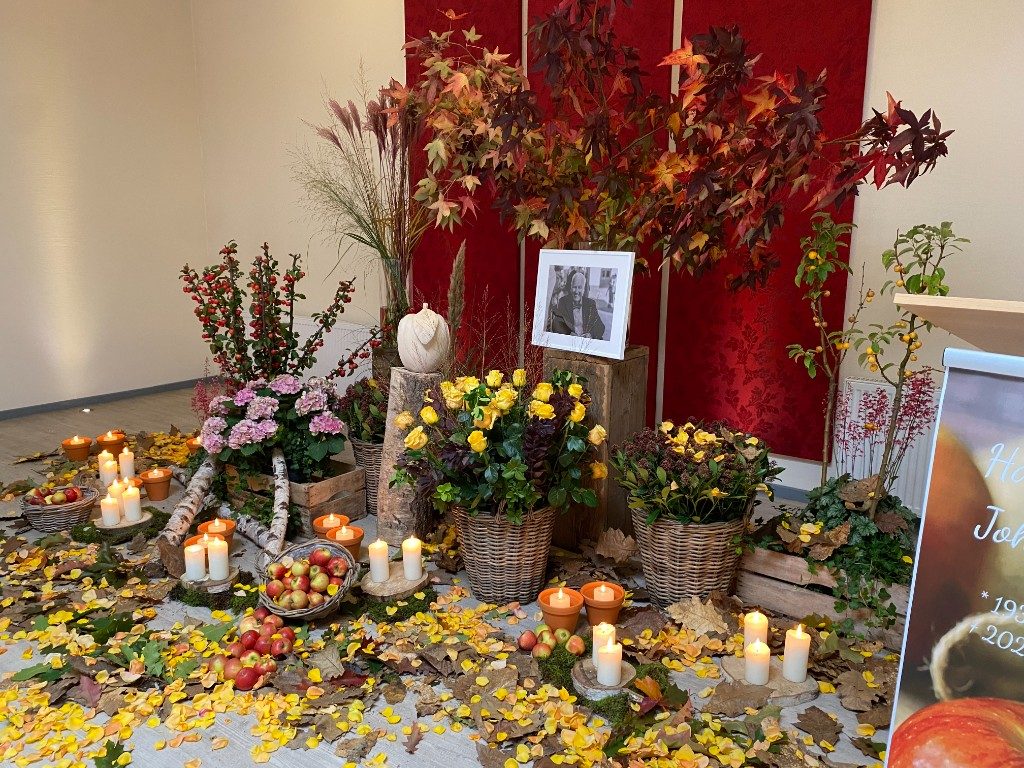 Herbstliche Dekoration mit Äpfeln, gelben Rosen und Kerzen bei einer Lebensfeier